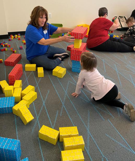 A Community Partner plays blocks with a young child during the parent/child workshop.