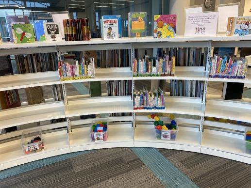 A glimpse at our curved play space shelves. Each section contains toys in labelled, clear bins and board books sorted by category.