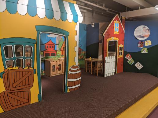 Child-sized pretend store-fronts and house buildings create a colorful space for pretend play.