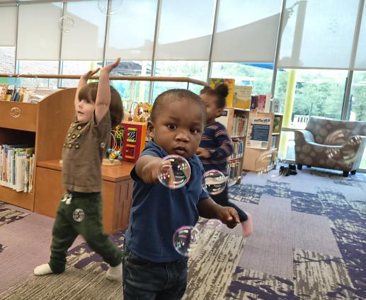 Toddler popping bubbles at an Early Literacy program.