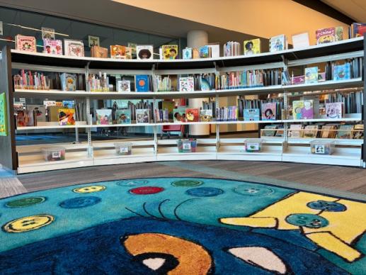 Curved play area with labelled toy bins, board books, and a Pete the Cat rug