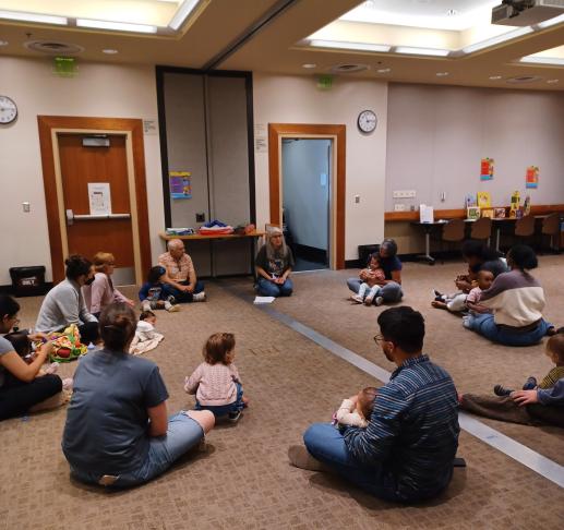 Photograph of families sitting in a circle listening to early literacy presentation 