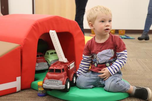 otto sits on green mat and plays with a toy firetruck.