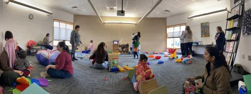 Room filled with children and adults playing.