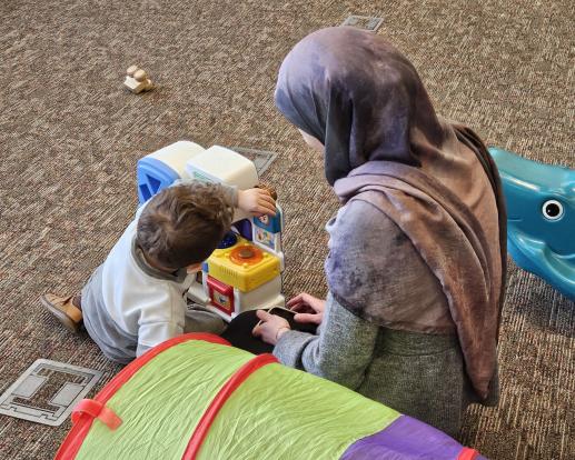 Mother and child play with toy kitchen