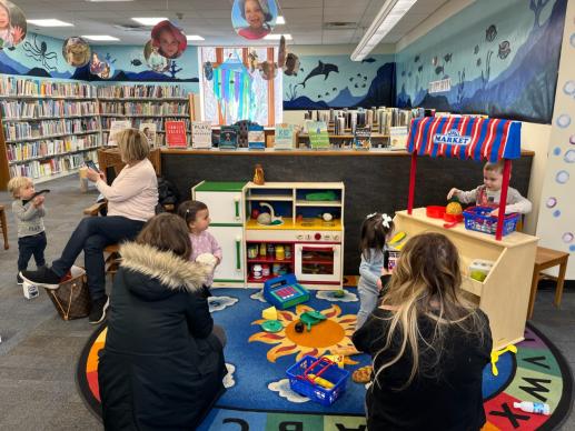 Kids and parents playing in the kitchen and market area of the Children's play space.