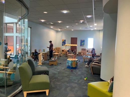 A large room with a glass wall filled with toys and people playing. 