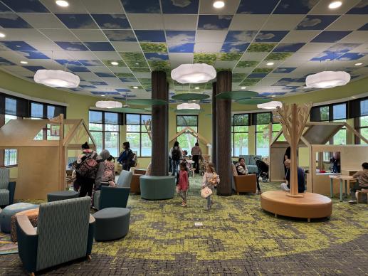 nature themed indoor play space area filled with families. 