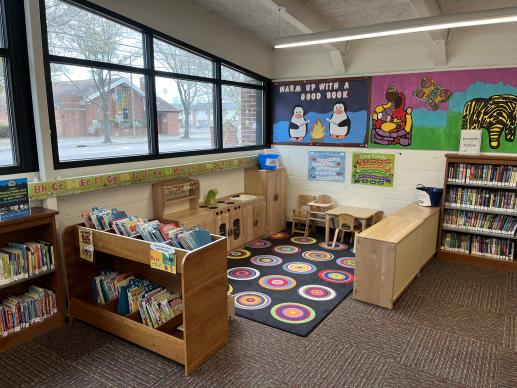 Blyden's KidZone, featuring a wooden toy kitchen, shelves filled with toys, all surrounded by bookshelves.