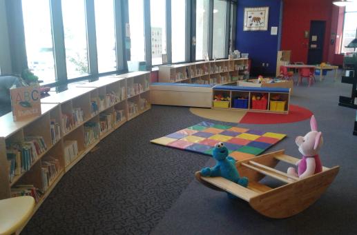 Play area with books, rocking boat, stuffed animals, and play mat.