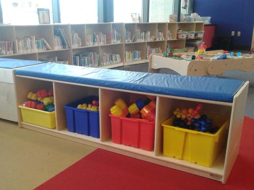 Play area with train table and various toys in bins.
