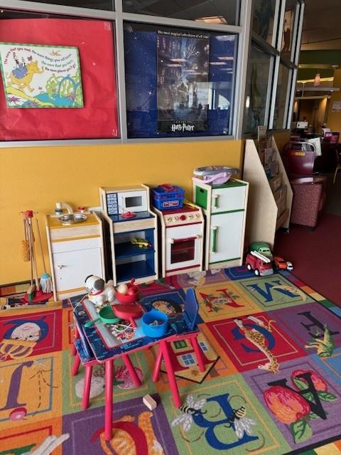 Play area with kitchen in view and toys strewn about after a busy day of use