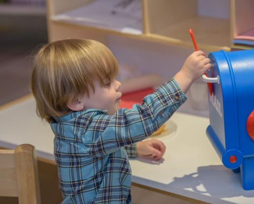 A child plays with a toy mailbox
