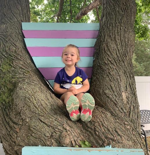A child poses from the library's Discovery Backyard climbing tree.