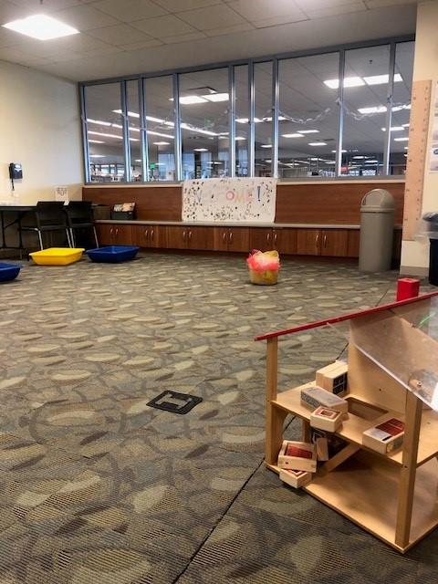 Picture of the room we use for the parent-child workshop--colorful bins in rear, large clear plastic bin of juggling scarves and our ever popular doll house complete the pic