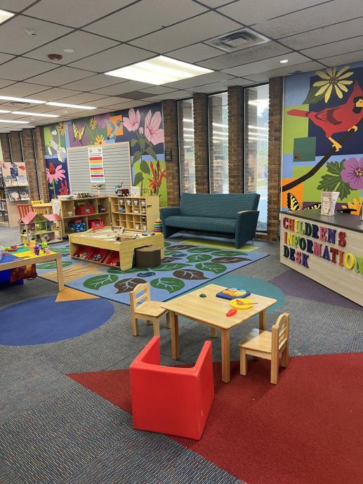 An image of Marple Public Library's children's area, with children's reference desk, train table and couch for reading.