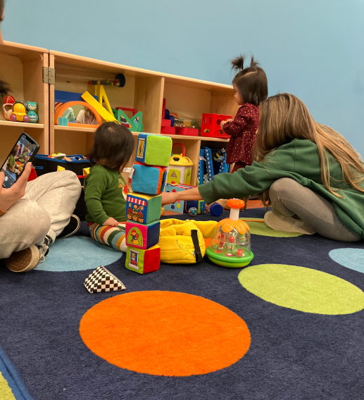 parents and children on bright carper playing with toys.