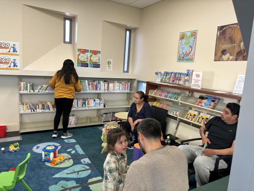 Parents watch their children play inside the Family Place, one mother reads a book from the parenting collection. 