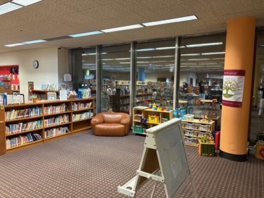 Another view of the play area showing the board books, oversized chair, easel, and toys.