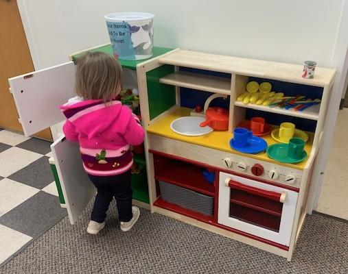 Child playing with play kitchen