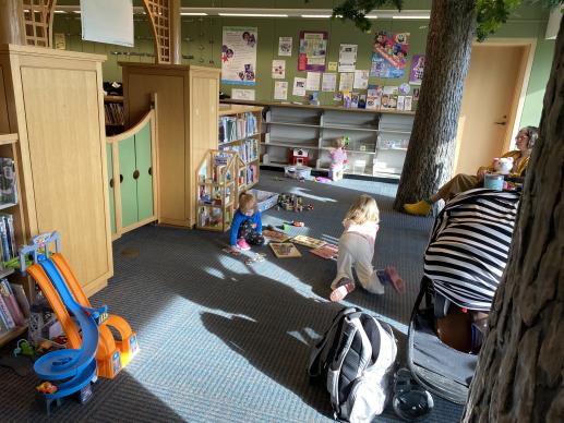 Families enjoying our Family Place play area that features a doll house, car track, manipulatives & more.