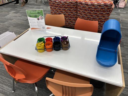 Children's writing table with crayons, paper, and toy mailbox.