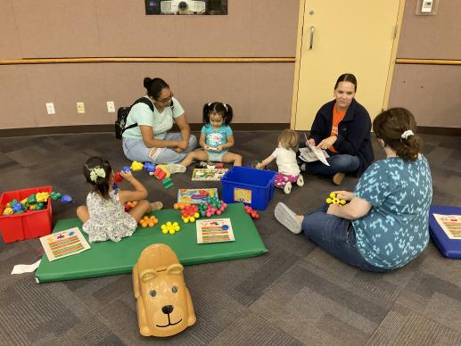 A group of adults and children playing with toys and talking.