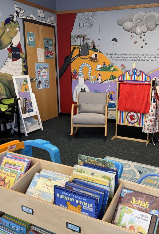 Children's area includes a dress up space, rocking chair, puppet theater and forward facing shelves