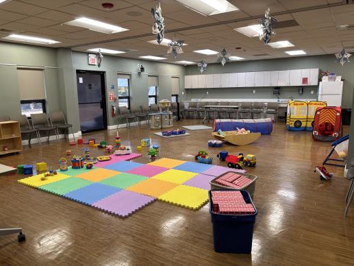 Classroom set up for Parent Child Workshop with foam matt, blocks, kitchen, tunnel and toys on the floor.