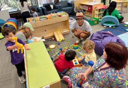 Children and caretakers play with toys and talk amongst themselves.