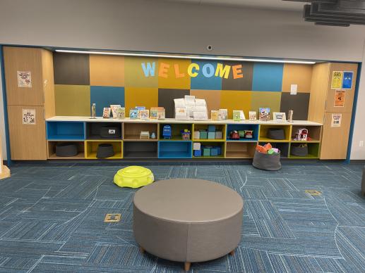 Play area with colorful wall and shelves housing toys. 