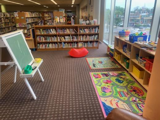 APL Family Place area showing toys, rugs, easel, and board book collection.