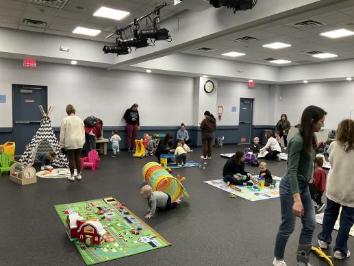 Children and adults playing at various toy stations. 