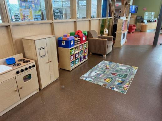 Play area showing toy cubby, play kitchen and colorful rug.