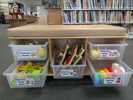 A storage bench with five drawers full of toys for infants.