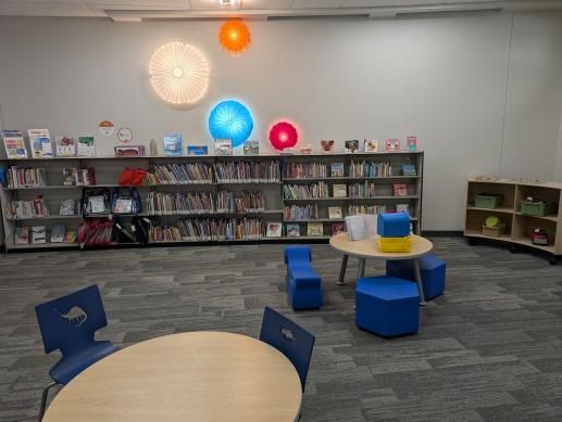 Enclosed children's space with tables, writing opportunities, toys, and parent resources.
