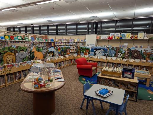 Children's area playspace with toy display, writing center, and comfy reading chairs
