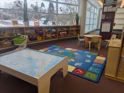 a small space in a public library with toys a brightly colored rug, with toys