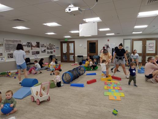 Caregivers and children playing with variety of toys in a large room