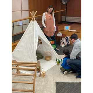 Caregivers playing with child in teepee