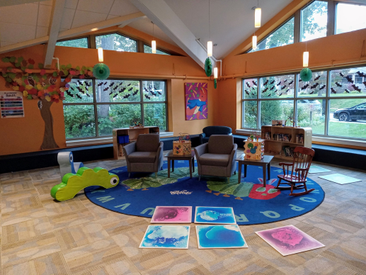 Play room with toys, comfortable chairs, and colorful artwork