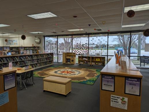 A children's play area in a library. It is colorful, neatly organized, and features many toys and books.