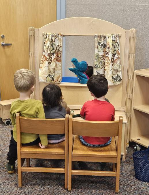 3 children watch a puppet show
