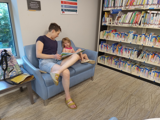 Caregiver and child reading together on a couch surrounded by books