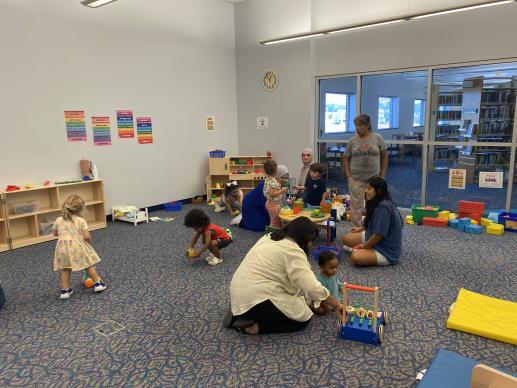 Children and caregivers playing with various toys during a Family Place Playgroup session.