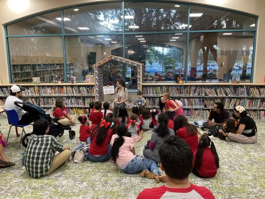 A group of children listen to the librarian read a book.