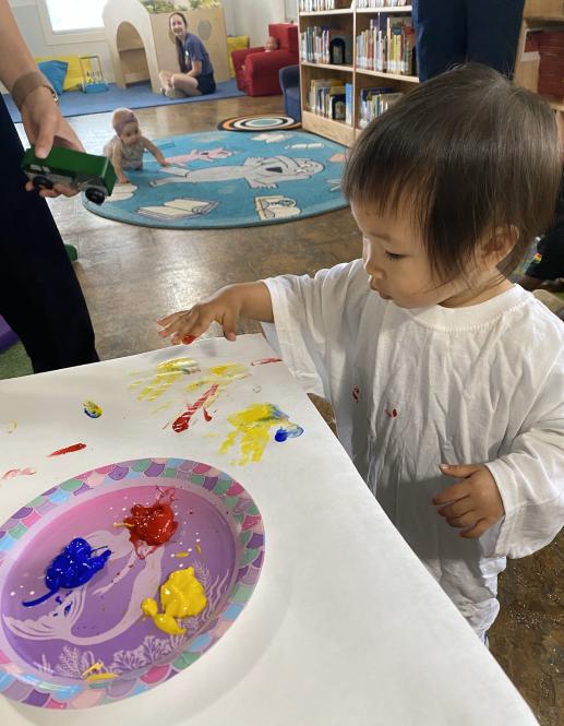 toddler finger painting wearing white smock