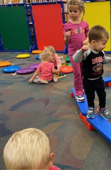 Family Place Library workshop with children exploring age appropriate toys and a balance beam.