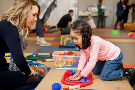 picture of parent child workshop. child playing with play doh with librarian.