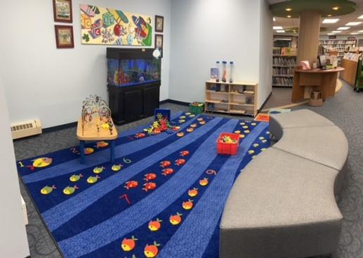 Open play area with fish tank, puzzles, building materials, seating and a fish tank.